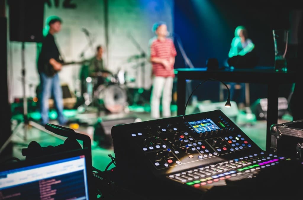 Console de mixage en régie, groupe sur scène en arrière-plan